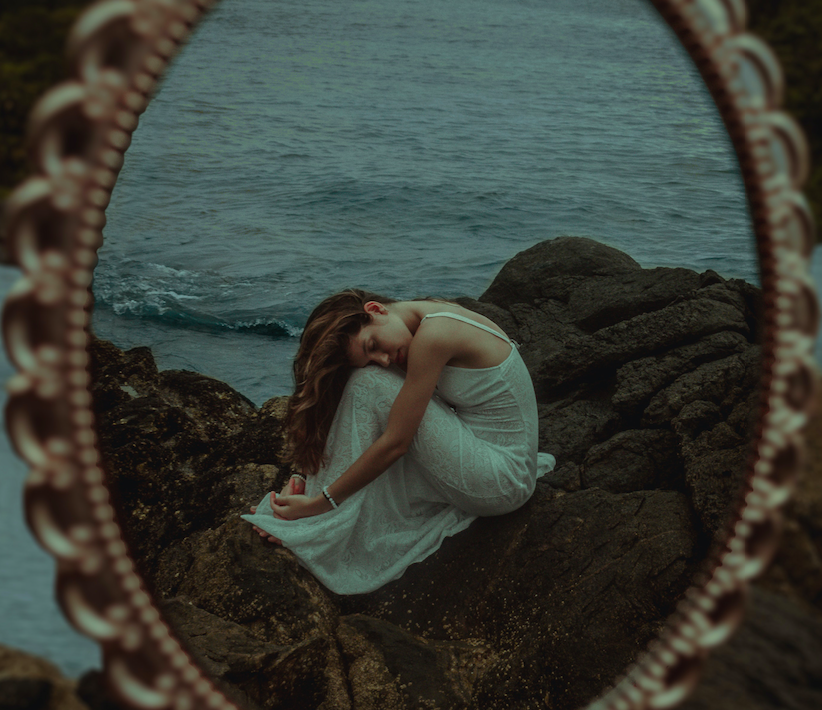 reflection of woman hugging herself on beach
